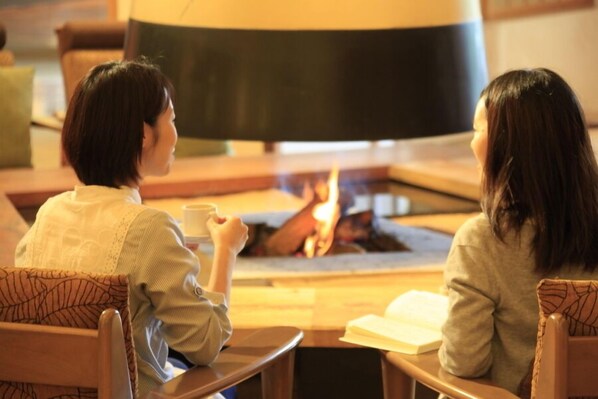 Two people sitting at a table with a fireplace in the background.