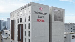 A modern hotel building with a prominent sign reading "Schweizer Dorf Hotel". - Schweizer Dorf Hotel (Cheonan)