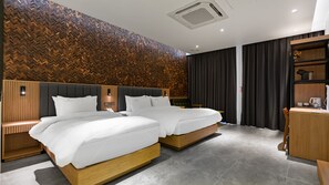 A hotel room with two beds, a wooden herringbone-patterned wall, a modern ceiling design, and a small desk with a lamp. - Schweizer Dorf Hotel (Cheonan)