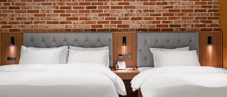 Una habitación de hotel con dos camas, un muro de ladrillo y un cabecero de madera.