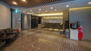 A modern reception area with a reception desk, a Christmas tree, and a small refrigerator. - Schweizer Dorf Hotel (Cheonan)