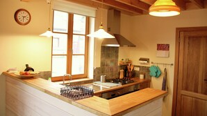 A kitchen with wooden beams, a large window, a sink, and a stove.