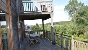A wooden deck with a table and chairs, overlooking a forested area.