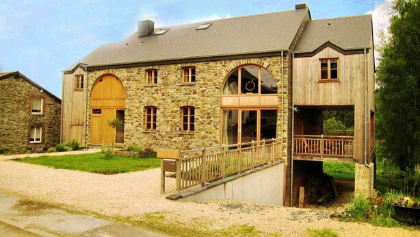 A stone building with a wooden balcony and a large arched window.