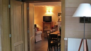 A wooden interior with a dining area, a television, and a lamp.