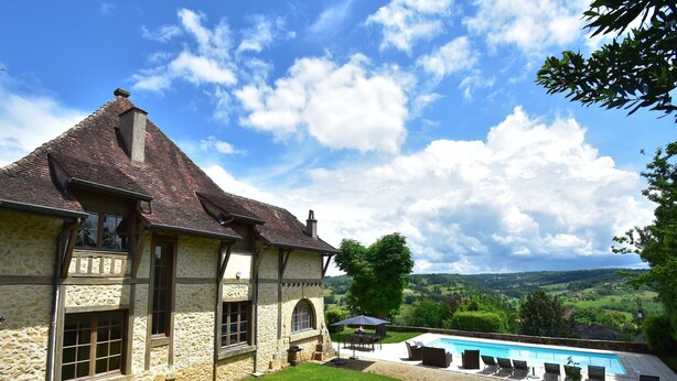 Una casa de piedra con piscina y vistas al campo.
