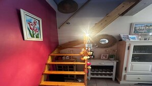 A wooden staircase with a light fixture, a painting of tulips, and a white cabinet with a mirror.