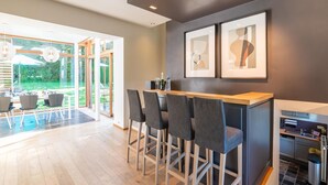 A modern kitchen with a bar area, a dining space with a view, and a small kitchenette.