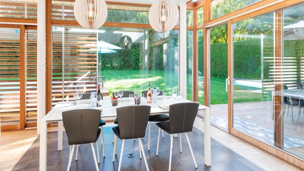 A modern dining area with a table set for four, large windows, and hanging pendant lights.