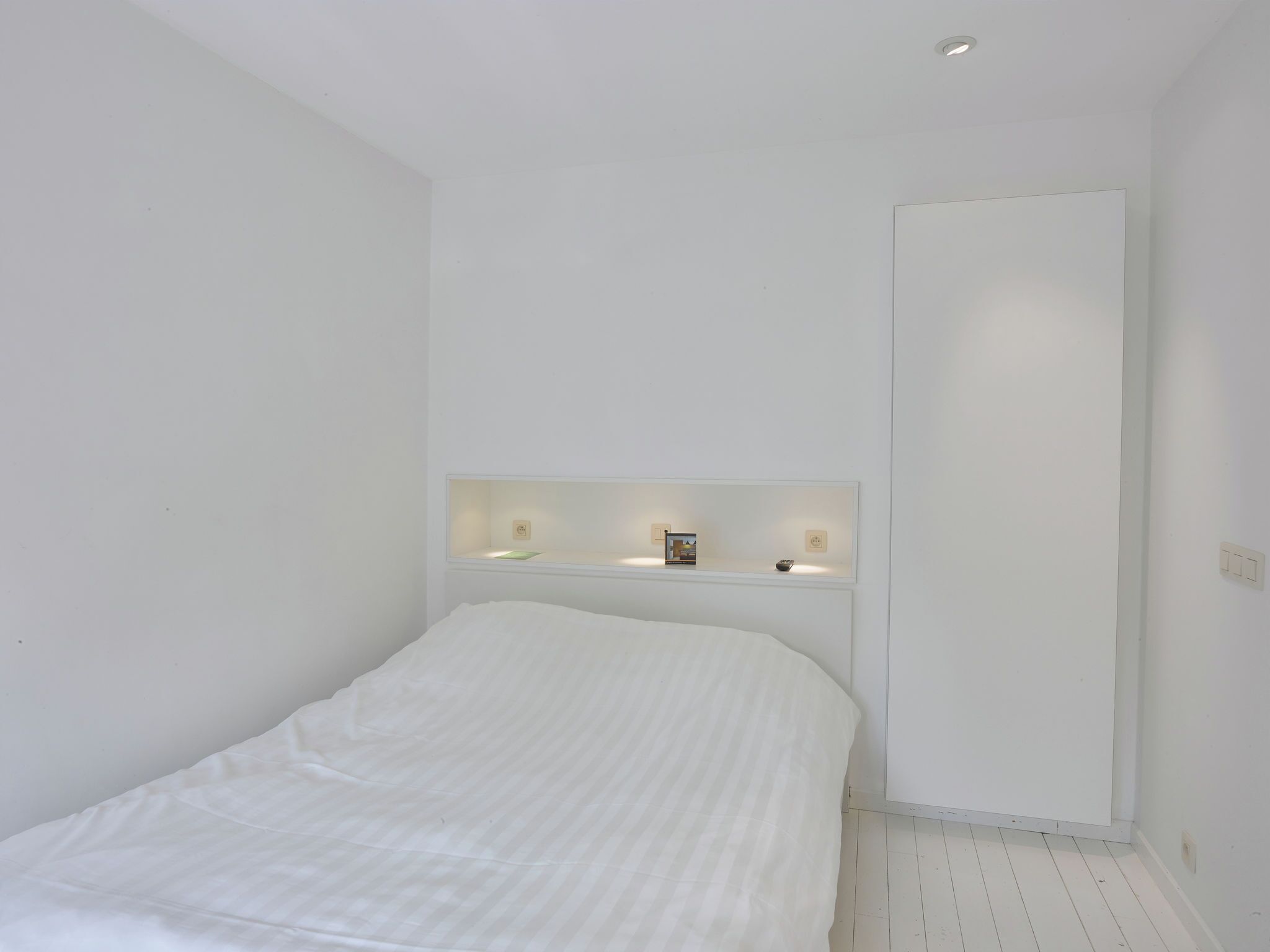 Un dormitorio minimalista con cama, mesita de noche y armario.