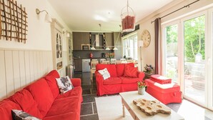 A spacious living area with red sofas, a white coffee table, and a kitchen in the background.
