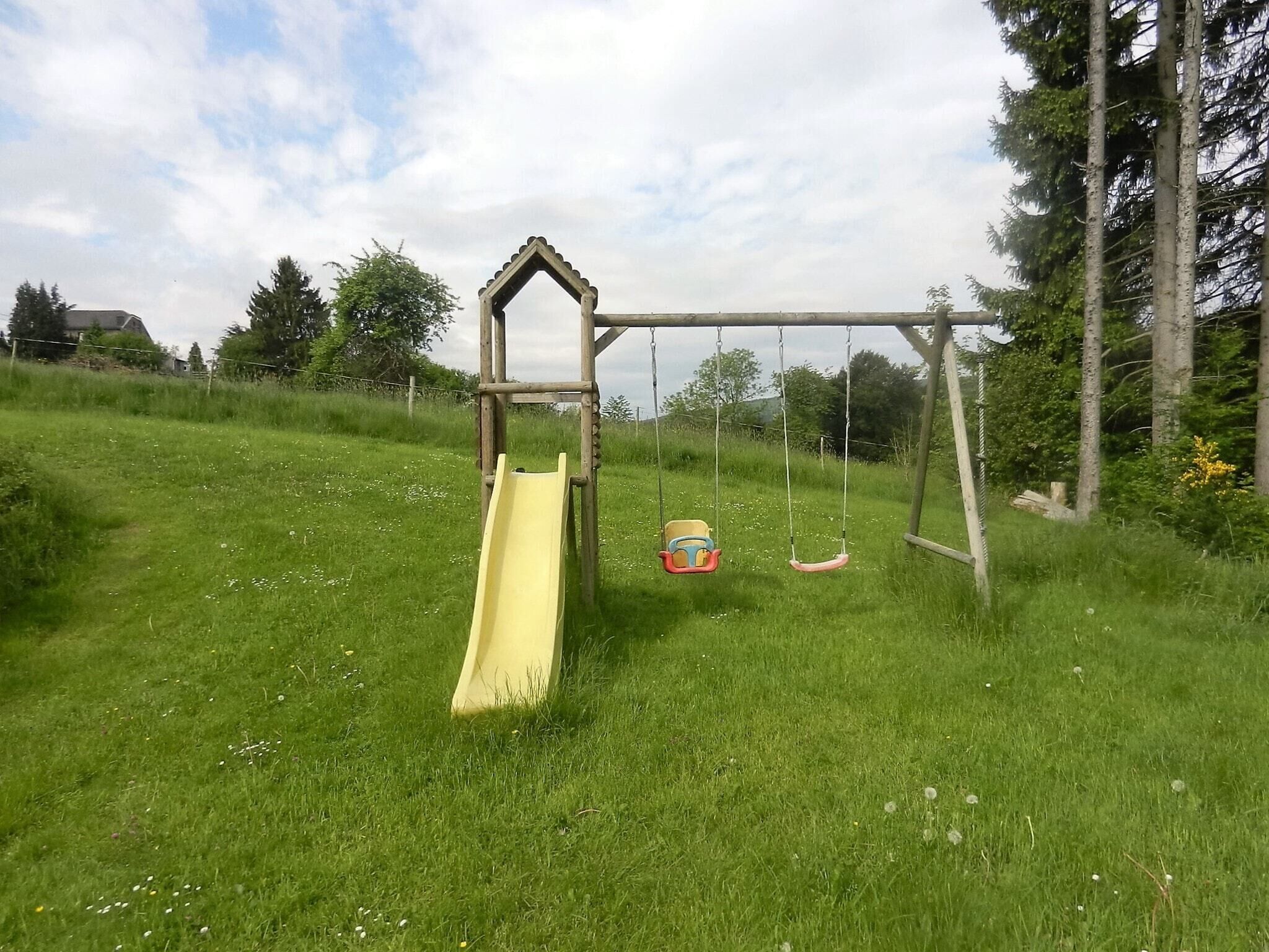 Un parc infantil amb un tobogan groc i cadira d'osc lleure.