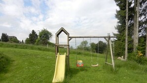 A playground with a yellow slide and swings. - The charm of a wooden chalet with a magnificent view, not far from Spa (Stoumont)