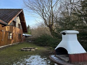 Situated in a secluded forest, this cabin features a chimney and stone fireplace.