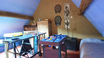 Relax in this cozy attic room with a unique sloped ceiling, featuring a comfortable bed and a dartboard for leisure activities.