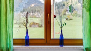 A window with two blue vases containing dried plants and flowers, a wooden door, and a view of a green landscape. - Apartment in Matrei near Ski Slopes (Matrei in Osttirol)