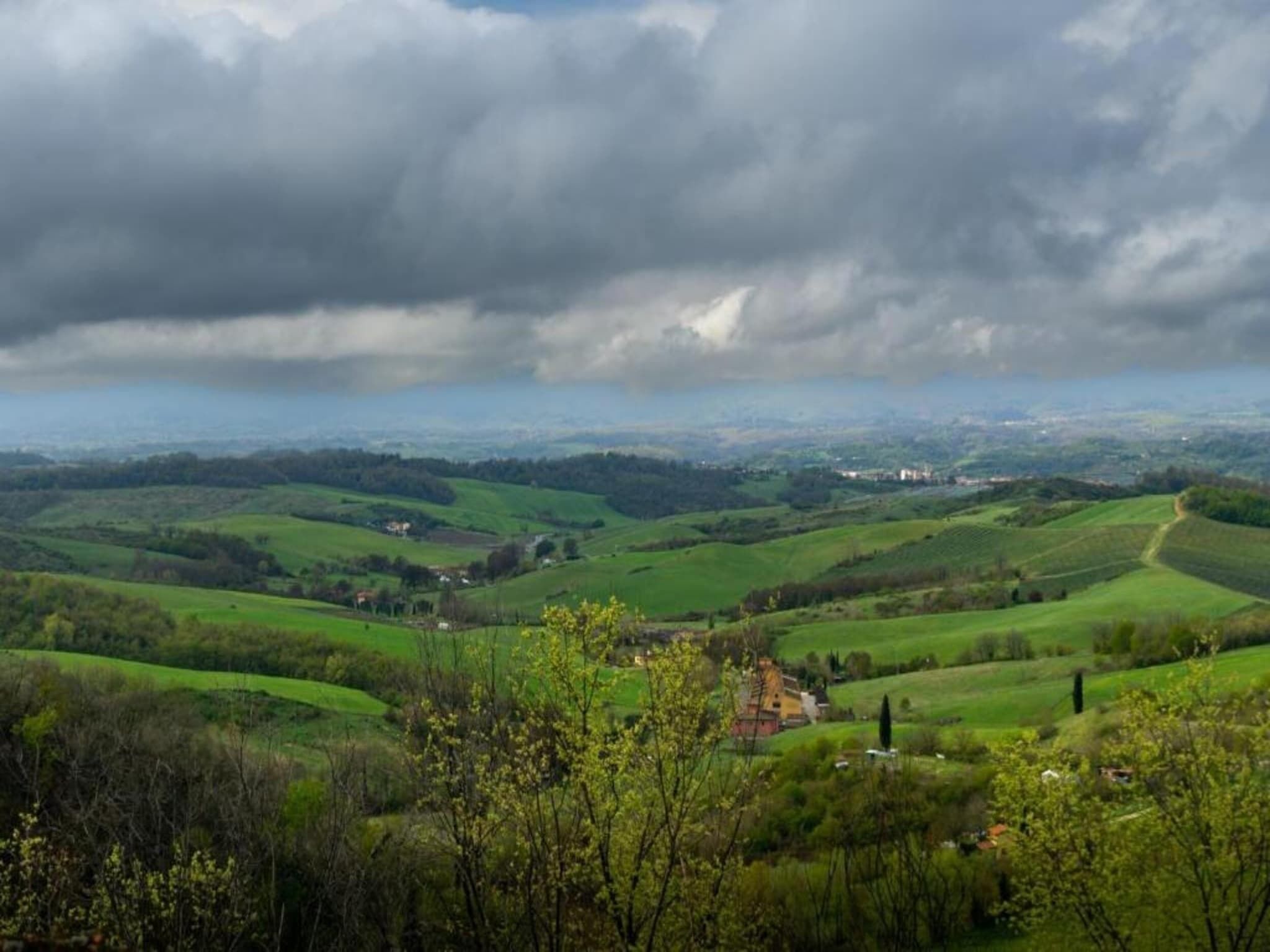 Une vue panoramique sur des collines verdoyantes et vallonnées, avec un petit village situé au fond de la vallée.
