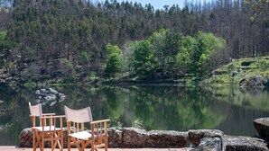 A lakeside patio with two wooden chairs and a stone wall.