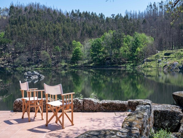 A lakeside patio with two wooden chairs and a stone wall.