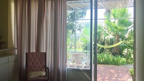 A room with a large sliding glass door leading to an outdoor area with a thatched roof and greenery. - Belvilla by OYO Menotti (Trecase)