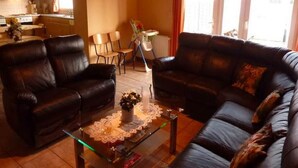 Un salon comprenant deux canapés en cuir, une table basse en verre et un coin repas avec des chaises.