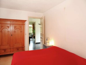 Relax in this inviting room with a comfortable bed, a small table, and a balcony with a chair and a plant.