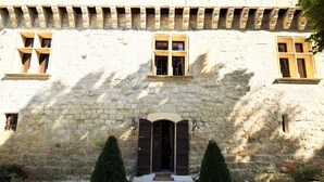 A stone building with a central entrance, two windows on either side, and a small door. - Cozy House in Lot with Pool and Terrace (Bon Encontre)