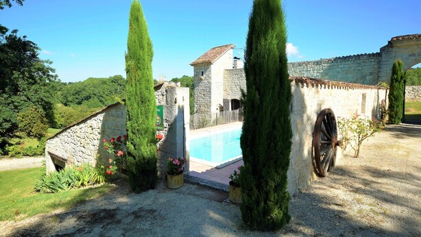 A stone building with a swimming pool, surrounded by tall cypress trees and a gravel path. - Cozy House in Lot with Pool and Terrace (Bon Encontre)