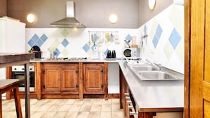 Una cocina compacta con armarios de madera, horno empotrado, microondas y pileta de acero inoxidable.