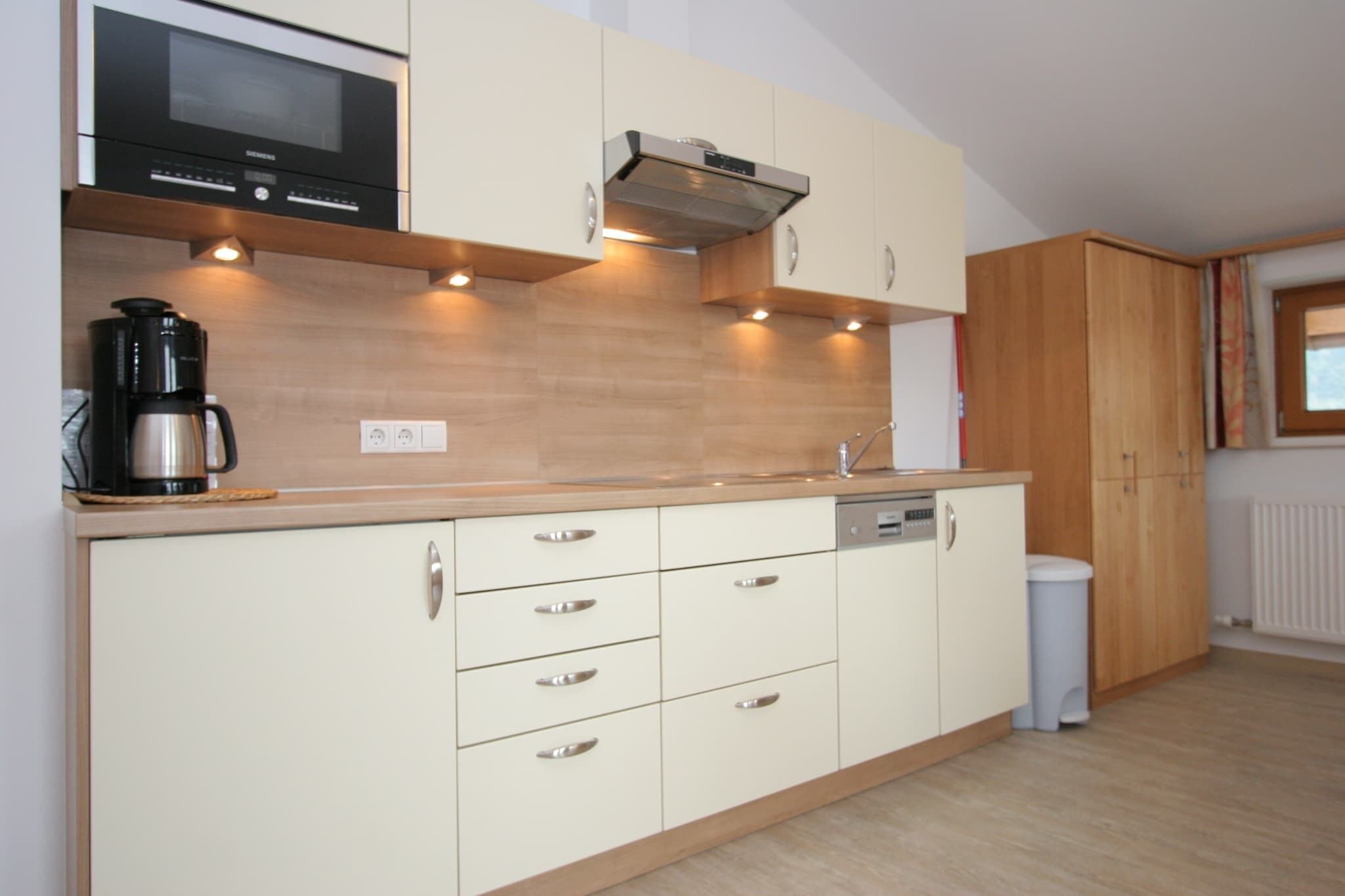 A modern kitchen with a built-in microwave, a coffee maker, and a dishwasher.