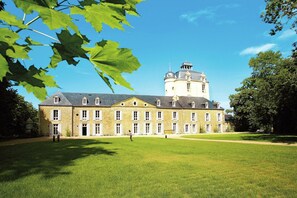 A large stone building with a central tower, surrounded by a well-maintained lawn.