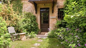 A stone building with a wooden door, a bench, and a stone pathway leading to the entrance. - Holiday Home in Dordogne near Lascaux Cave (Les Eyzies-De-Tayac-Sireuil)