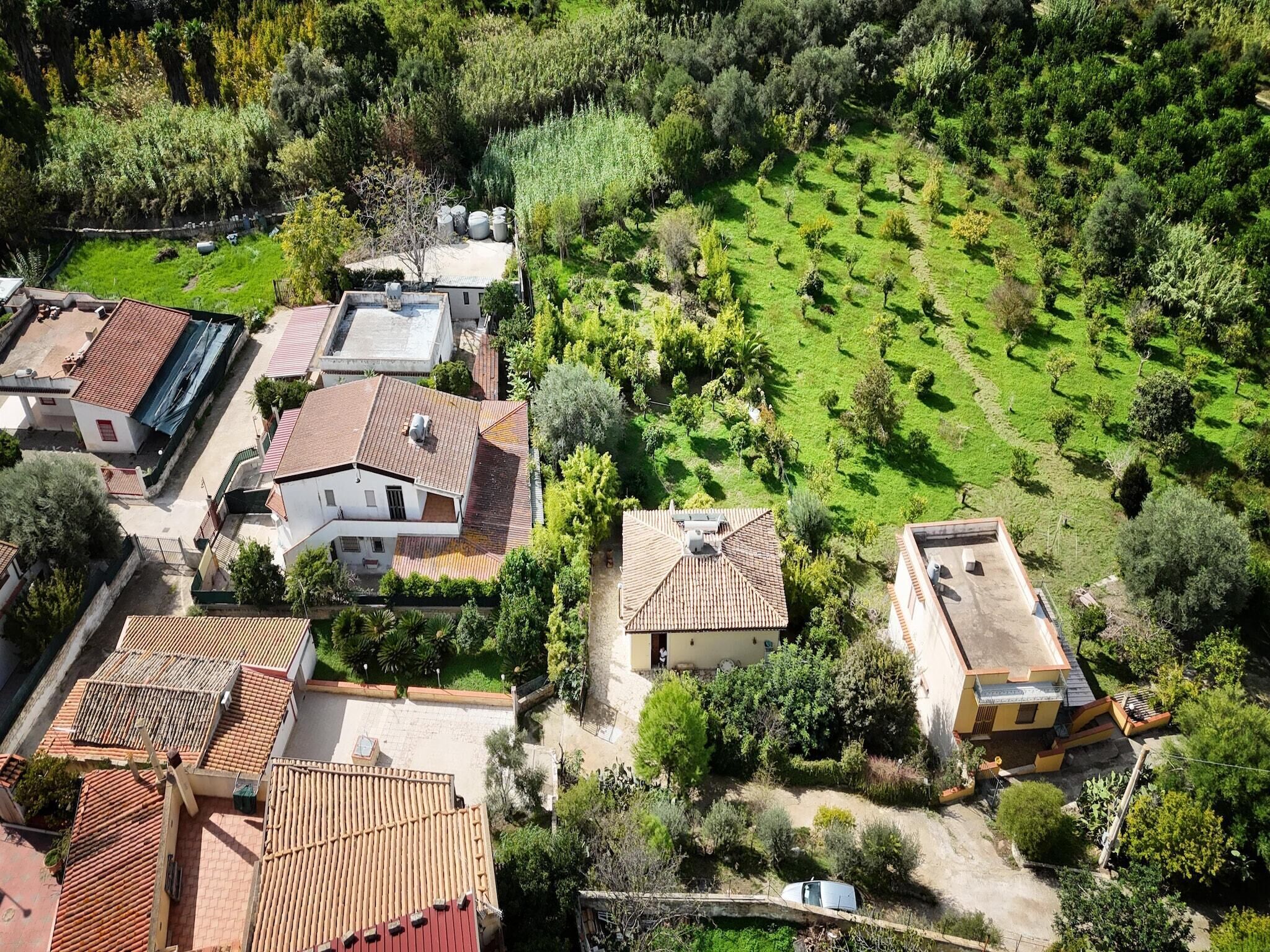 An aerial view of a residential area with houses, a well-maintained garden, and a clear road.