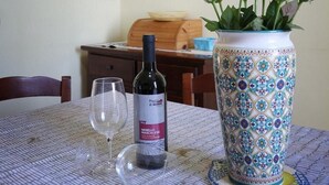 A dining table with a wine bottle, glasses, and a decorative vase. - Holiday Home in Lido di Noto near Beach (Lido di Noto)
