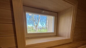Een houten hutje met een raam dat uitkijkt op een bos.