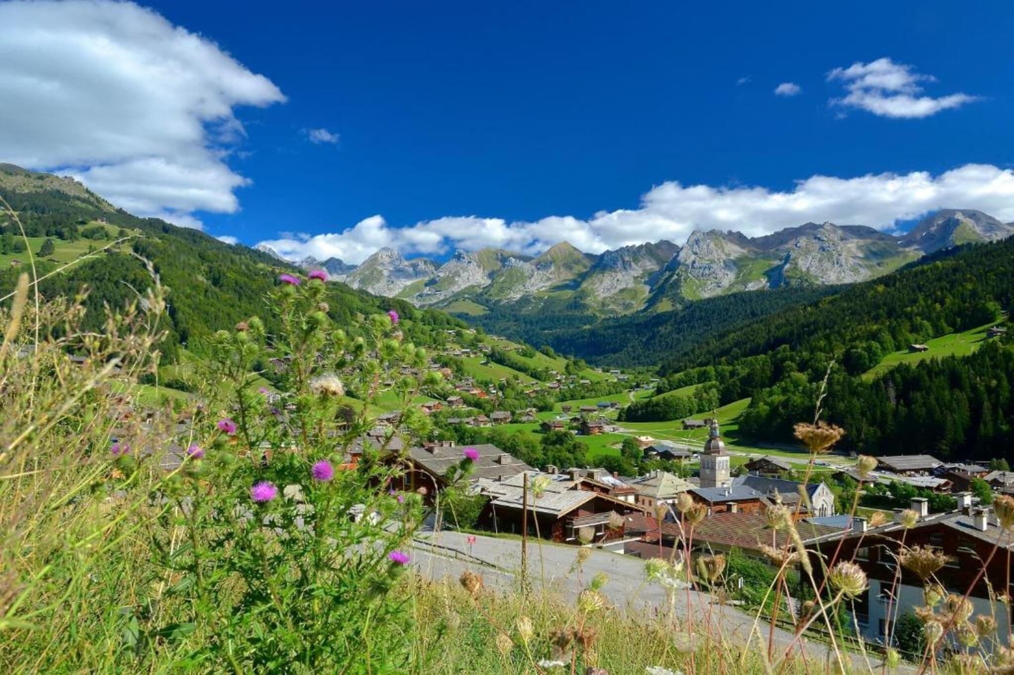 A mountainous village with traditional houses, a church, and a clear sky.