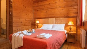 A wooden room with a bed, two bedside lamps, a nightstand, and a window with curtains. - Apartment in Evian with Lake Geneva View (Bernex)