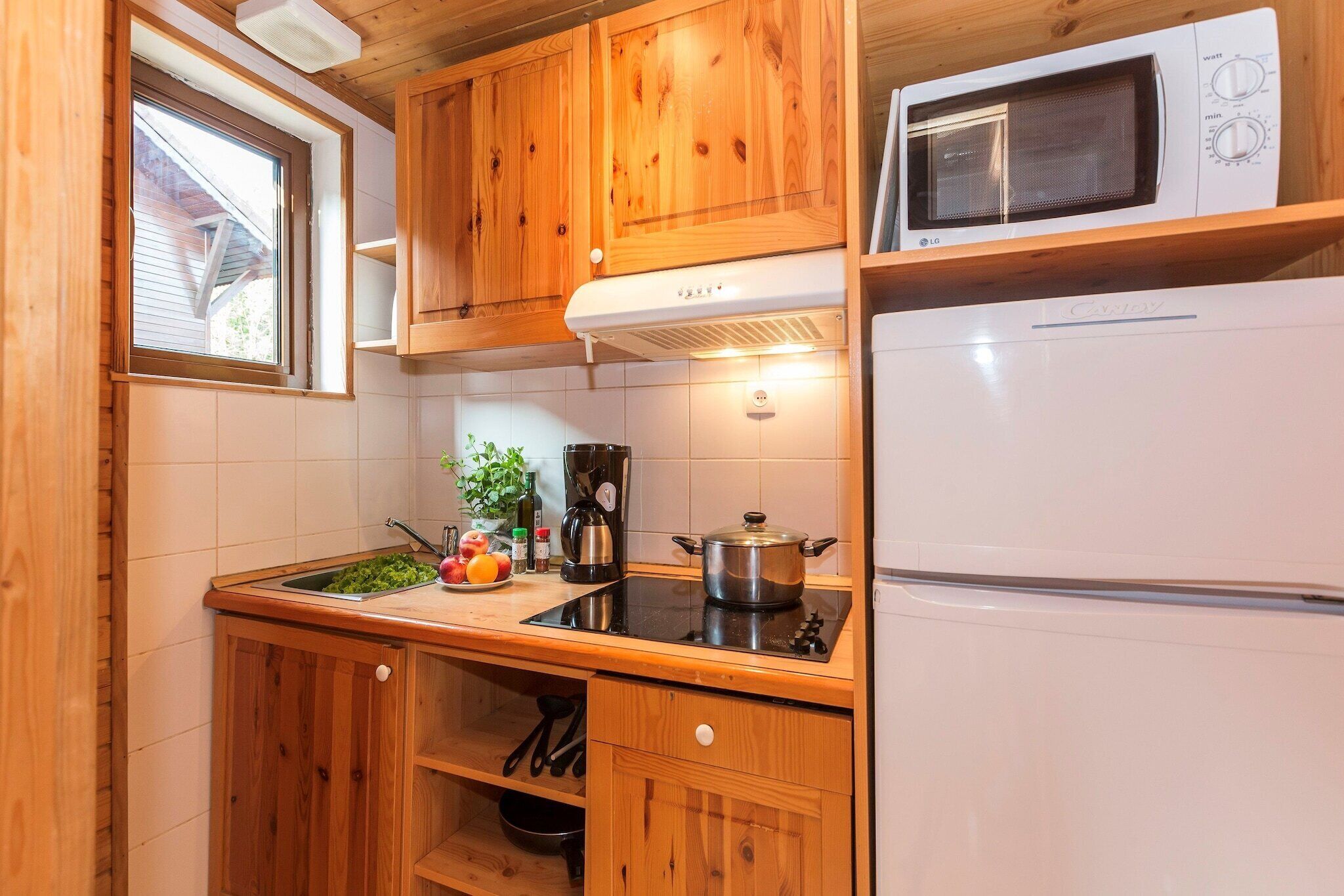 Une cuisine de taille réduite, dotée de meubles en bois, d’un four à micro-ondes, d’une cuisinière et d’un réfrigérateur.