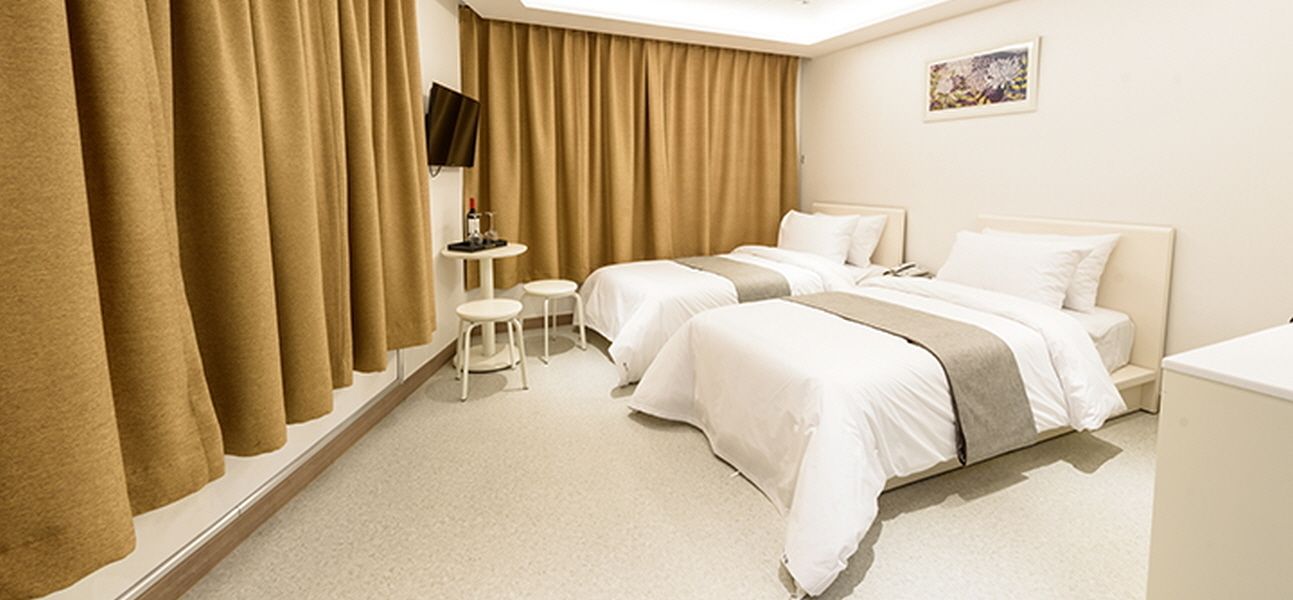 Una habitación de hotel con dos camas, televisión, una mesita y una silla.