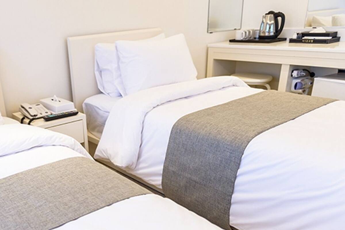Ein Hotelzimmer mit zwei Betten, einem Schreibtisch mit Telefon und einer Kaffeemaschine.