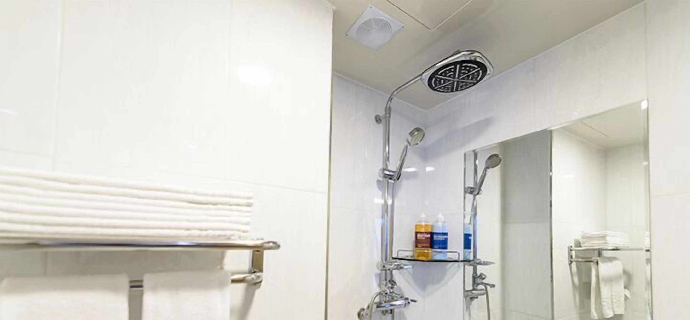 Ein modernes Badezimmer mit Duschkabine aus Glas, einem Handtuchhalter und einem Spiegel.