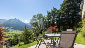 Une terrasse avec une table et des chaises, offrant une vue sur un paysage montagneux.