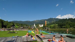 Una terrazza sul lago con piattaforme in legno, una piccola barca e un'antenna con bandiera.