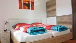 Una camera da letto con un letto con struttura in legno, una testiera bianca e un comodino con una lampada.