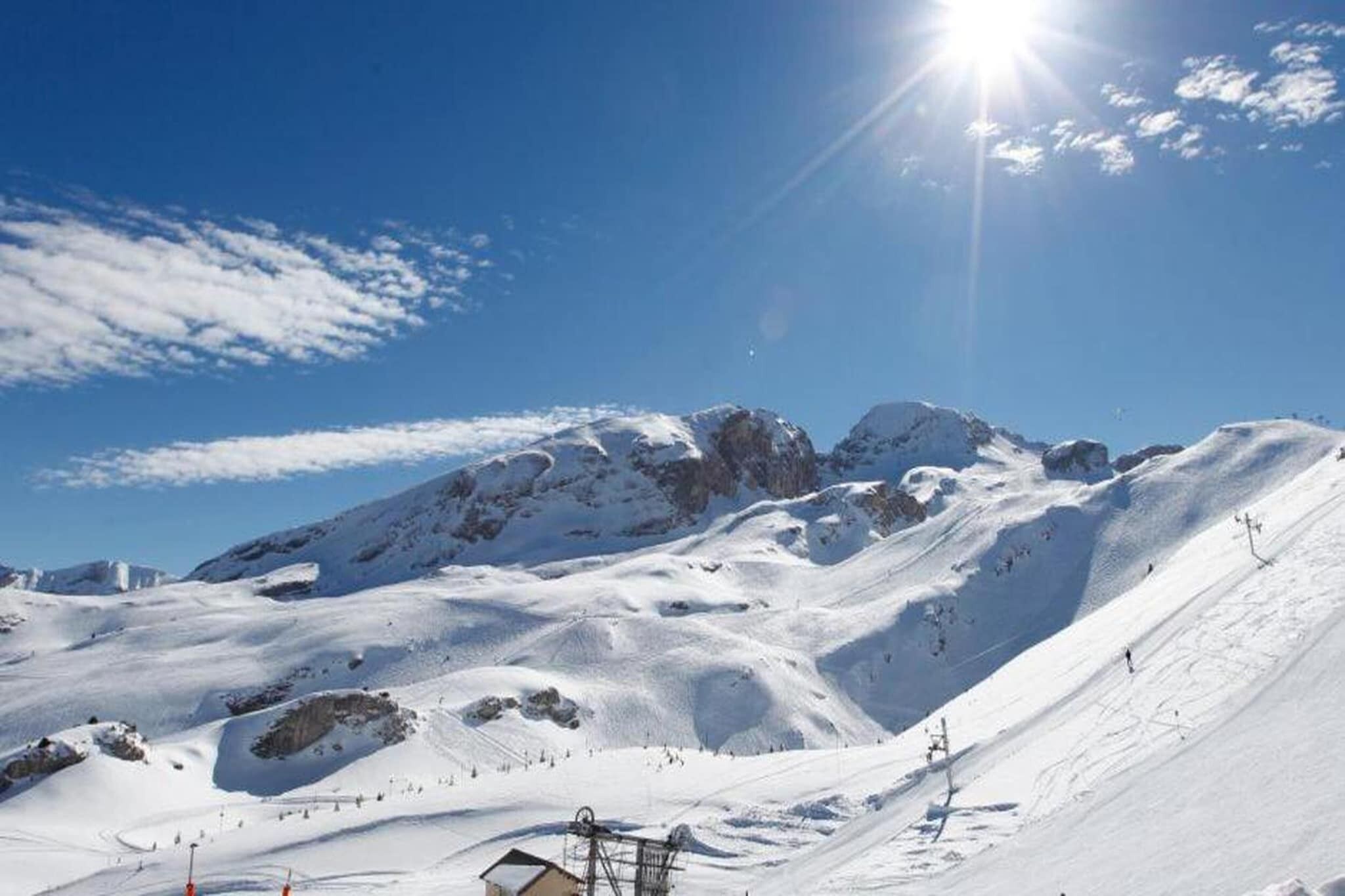 Une pente de montagne recouverte de neige, sous un ciel dégagé et un soleil éclatant.