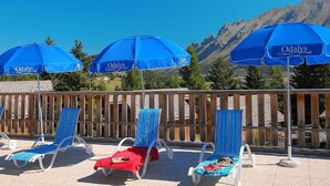 A poolside area with blue umbrellas and lounge chairs. - Spacious Alpine Chalet (Le Devoluy)