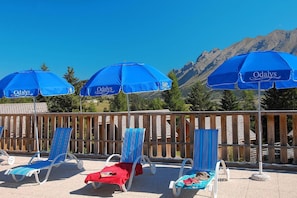 Ein Poolbereich mit blauen Sonnenschirmen und Liegestühlen.
