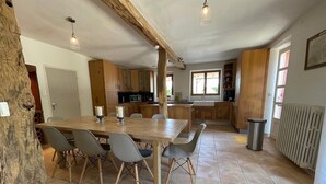 Une cuisine spacieuse dotée de meubles en bois, une table à manger avec des chaises et une grande fenêtre laissant entrer la lumière naturelle.