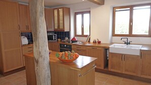 Une cuisine moderne avec des meubles en bois, un îlot central et une grande fenêtre qui laisse entrer la lumière naturelle.