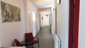 A corridor with a dining area featuring red chairs and a table, a radiator on the wall, and a painting on the left. - Child-friendly holiday home in Moravia with a beautiful location and view (Nedvedice)